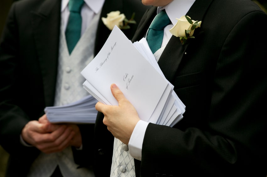 Wedding Ushers holding order booklets.